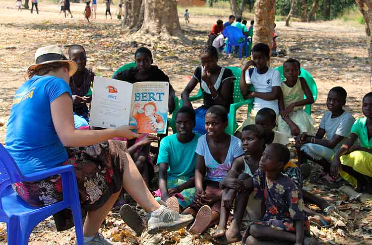 A volunteer reading to a group of young Malawi children